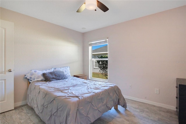 bedroom with a ceiling fan, light wood-style floors, and baseboards