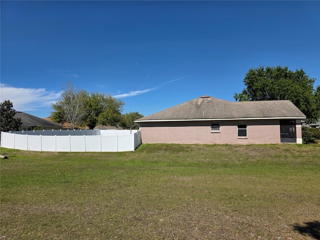 view of side of property with stucco siding, a lawn, and fence