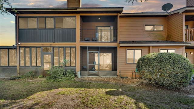 rear view of house featuring a balcony, a sunroom, and a chimney