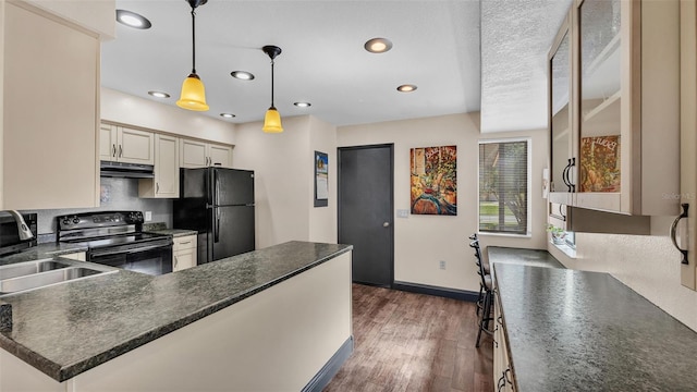 kitchen with under cabinet range hood, dark wood-style flooring, a sink, black appliances, and dark countertops