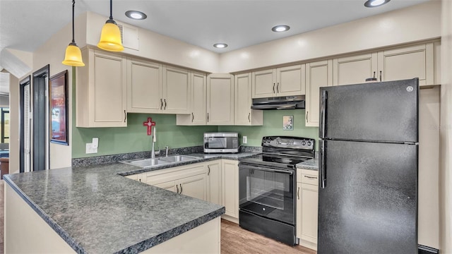 kitchen with dark countertops, a peninsula, under cabinet range hood, black appliances, and a sink