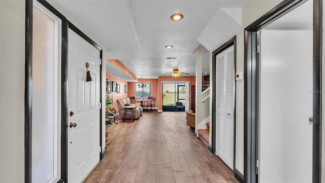 hall featuring light wood finished floors, baseboards, visible vents, stairs, and recessed lighting