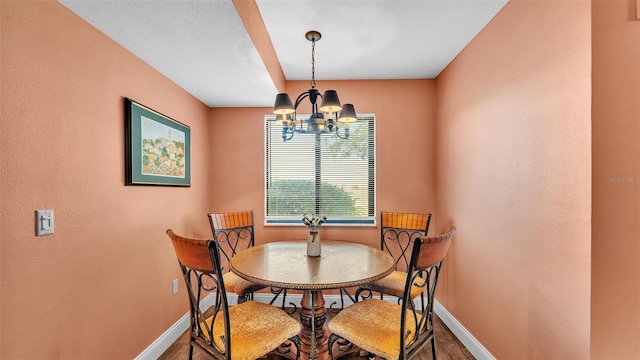 dining space featuring baseboards, wood finished floors, and an inviting chandelier