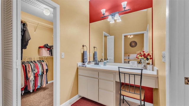 full bath featuring baseboards, a walk in closet, and vanity