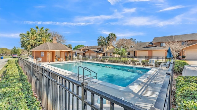 pool with a residential view, a patio area, and fence