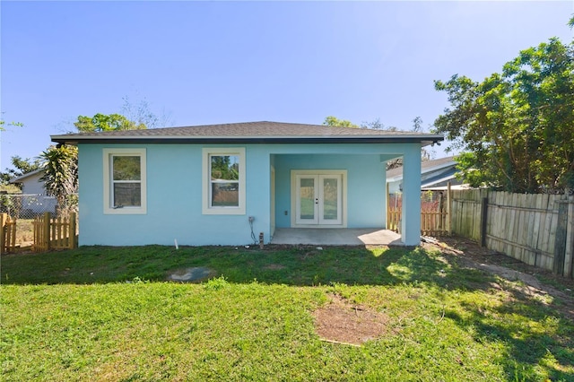 rear view of property with french doors, a lawn, a fenced backyard, and stucco siding