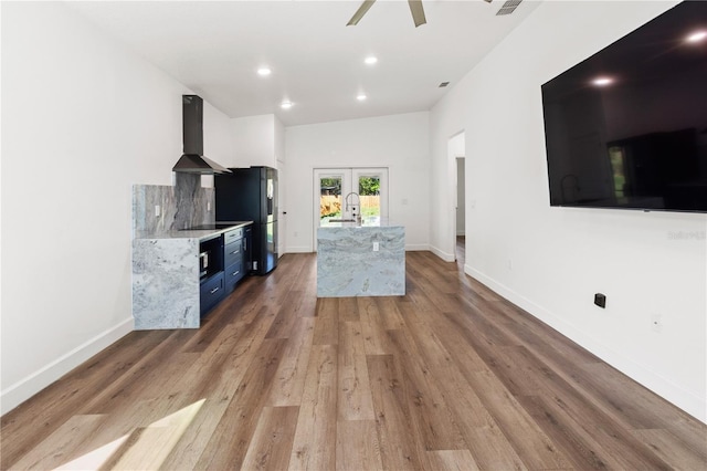 unfurnished living room featuring french doors, baseboards, light wood-style floors, and a sink