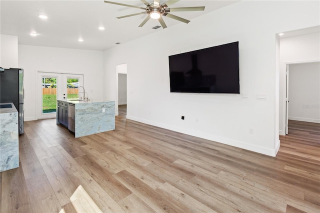 unfurnished living room with light wood finished floors, ceiling fan, baseboards, recessed lighting, and a sink