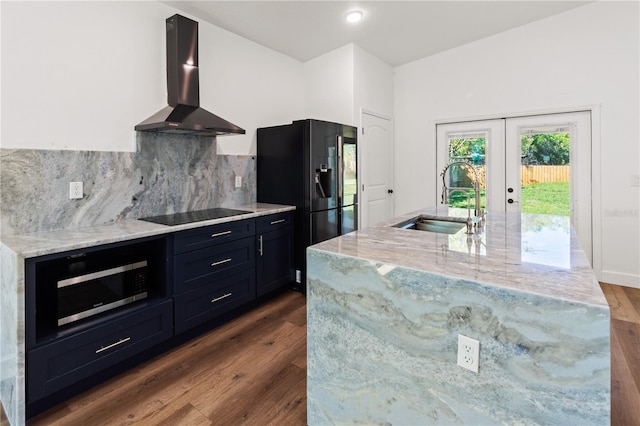 kitchen with ventilation hood, light stone countertops, black appliances, and a sink