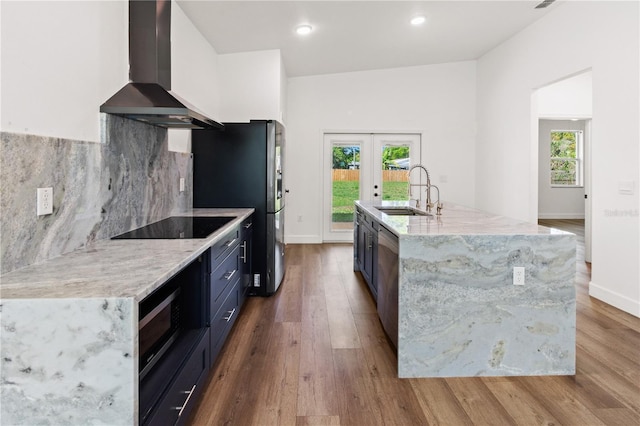 kitchen with backsplash, french doors, wood finished floors, wall chimney exhaust hood, and a sink