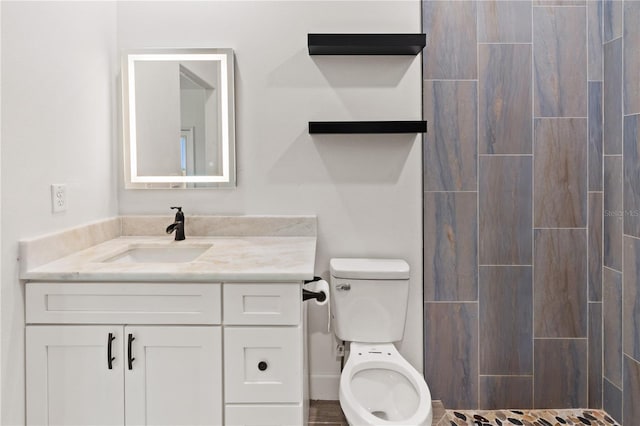 full bath featuring vanity, toilet, and a tile shower