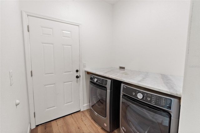 laundry room with laundry area, washing machine and dryer, and light wood-type flooring