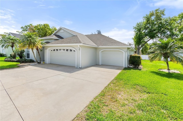 ranch-style home featuring a garage, driveway, roof with shingles, stucco siding, and a front lawn