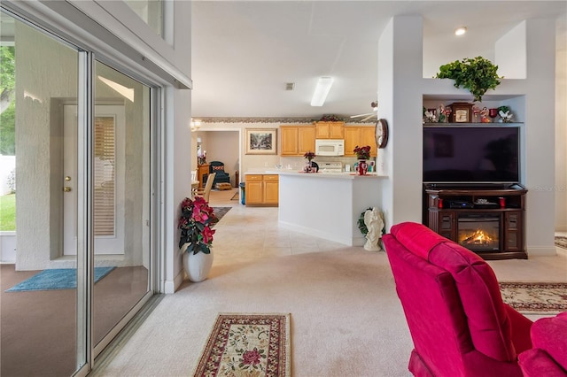 living room with a wealth of natural light, a glass covered fireplace, light carpet, and light tile patterned floors