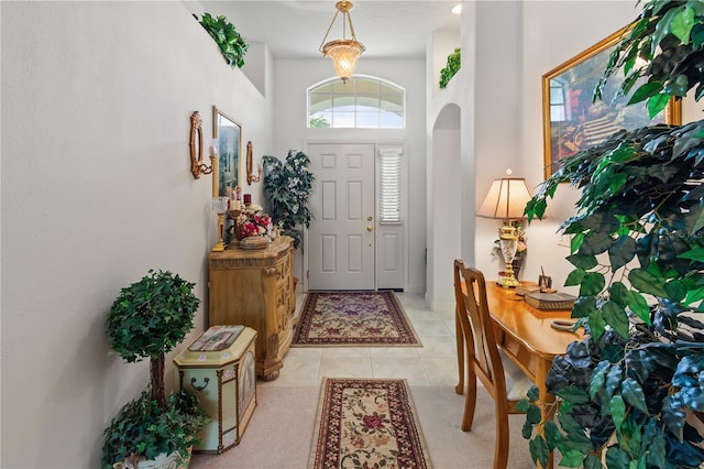 entryway with arched walkways and light tile patterned flooring