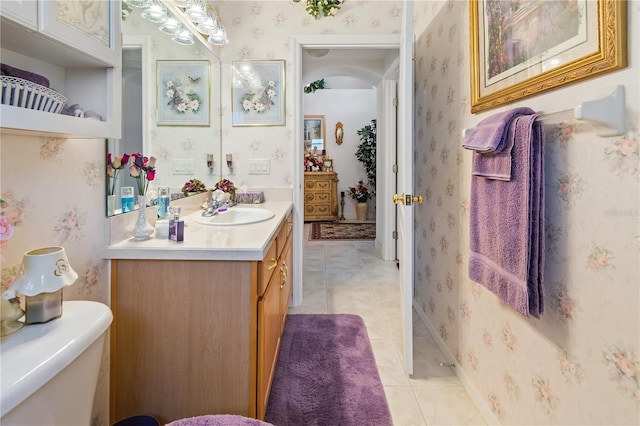 bathroom with toilet, tile patterned floors, vanity, and wallpapered walls