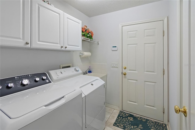 laundry room featuring a textured ceiling, washing machine and clothes dryer, and cabinet space