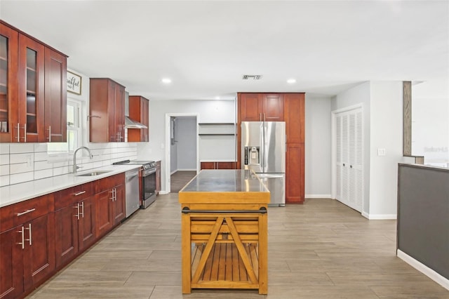 kitchen with appliances with stainless steel finishes, reddish brown cabinets, and a sink