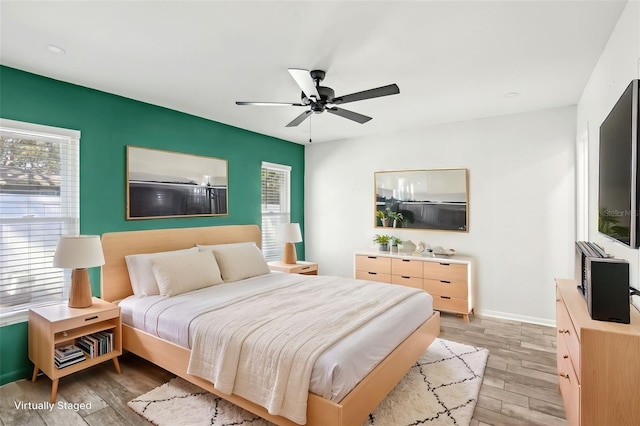 bedroom featuring ceiling fan, light wood-type flooring, and baseboards