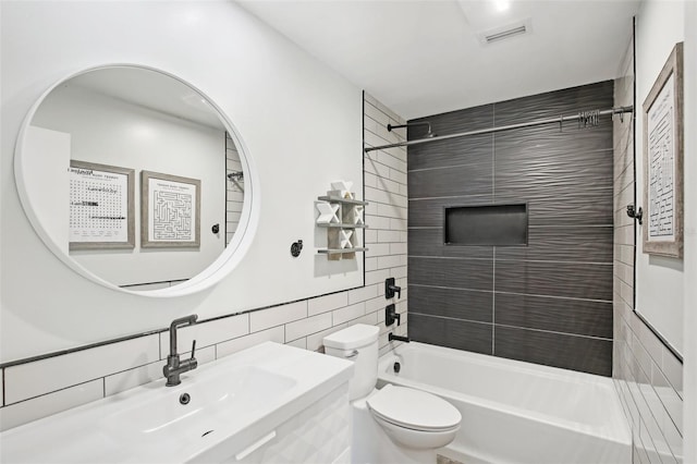 full bath with tile walls, visible vents, toilet, a sink, and shower / tub combination