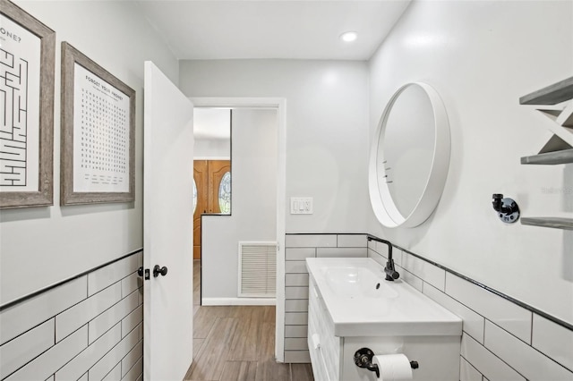 bathroom featuring visible vents, tile walls, vanity, and wood finished floors