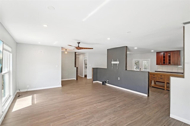 unfurnished living room with light wood finished floors, baseboards, and recessed lighting