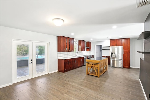 kitchen with french doors, backsplash, a sink, dark brown cabinets, and stainless steel fridge