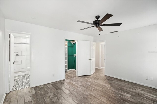 unfurnished bedroom featuring wood finished floors, visible vents, baseboards, a spacious closet, and a closet