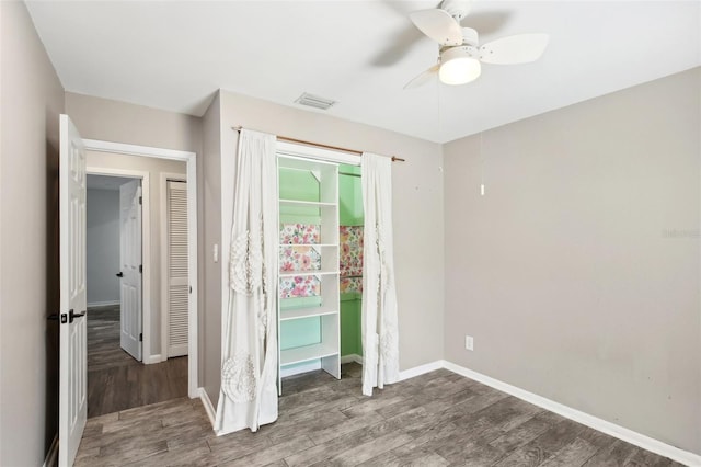 unfurnished bedroom with a ceiling fan, visible vents, baseboards, and wood finished floors