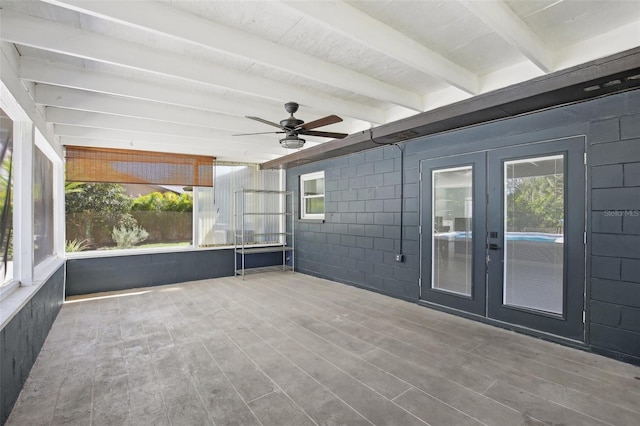 unfurnished sunroom featuring a ceiling fan, french doors, and beam ceiling