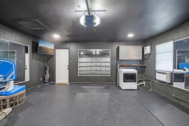 garage with washer / dryer, cooling unit, concrete block wall, and a garage door opener