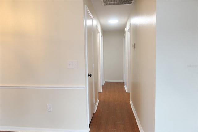 corridor featuring dark wood-type flooring, visible vents, and baseboards