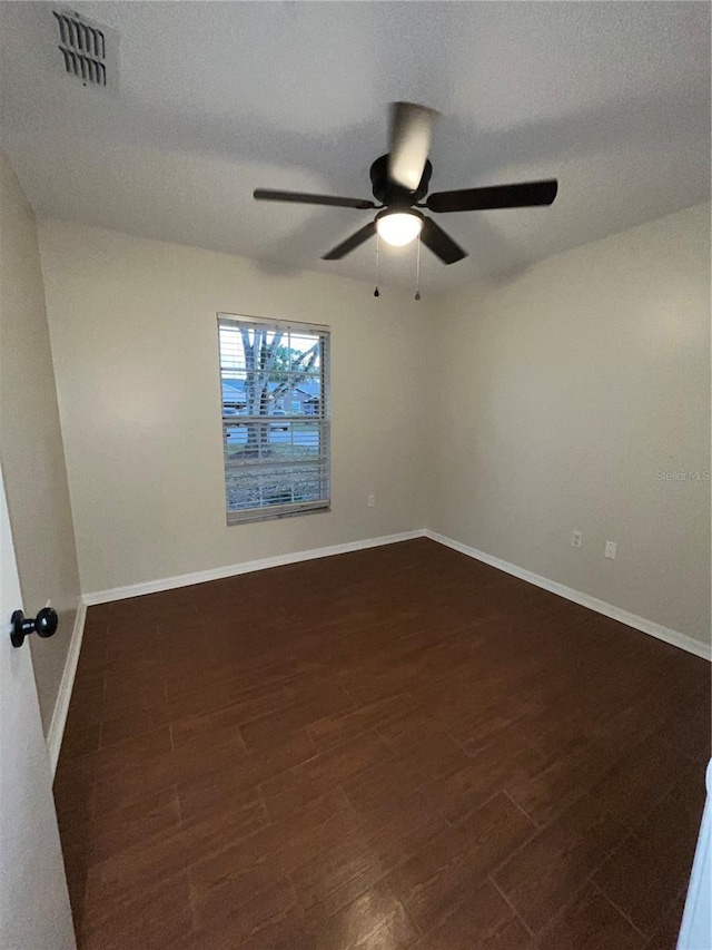 unfurnished room with a textured ceiling, ceiling fan, dark wood-type flooring, visible vents, and baseboards