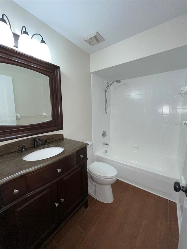 bathroom with bathtub / shower combination, visible vents, toilet, vanity, and wood finished floors