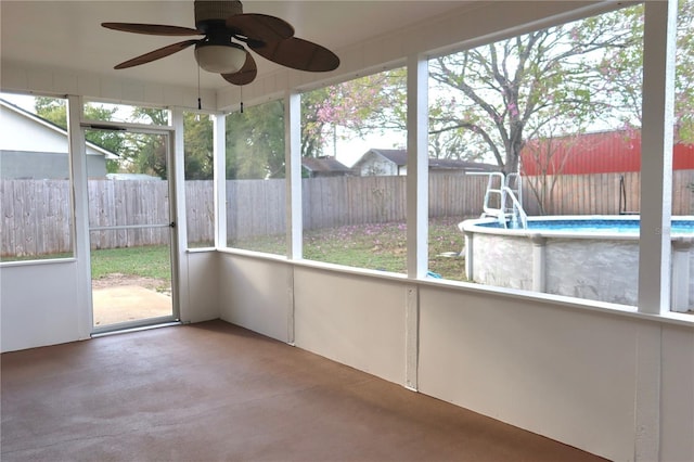 unfurnished sunroom featuring a ceiling fan and plenty of natural light