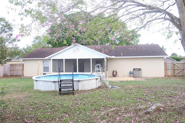 back of house with a yard, a fenced backyard, a sunroom, and a fenced in pool