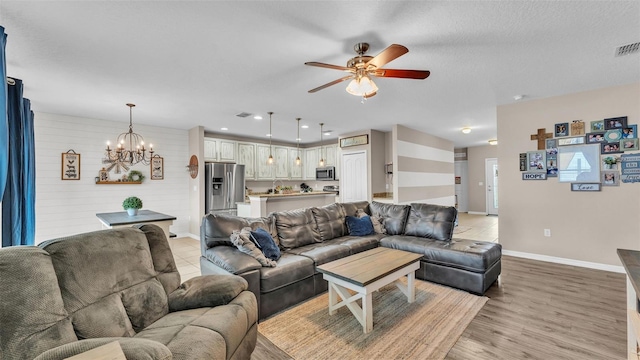 living room featuring light wood finished floors, recessed lighting, baseboards, and ceiling fan with notable chandelier