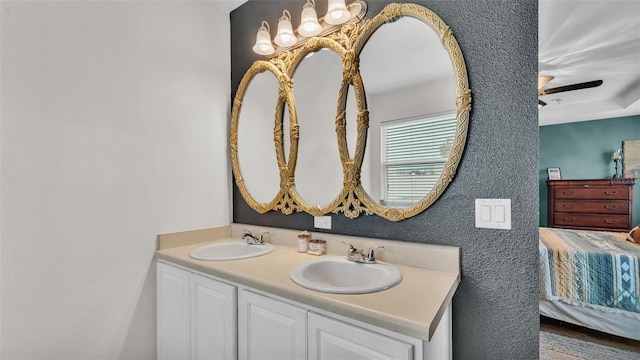 ensuite bathroom with double vanity, ensuite bath, a sink, and a ceiling fan