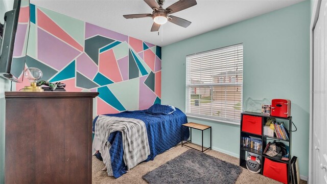 bedroom with ceiling fan, an accent wall, carpet floors, and baseboards