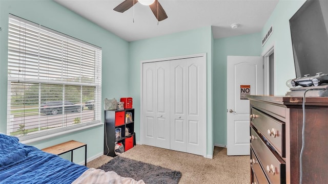 bedroom with visible vents, baseboards, light colored carpet, ceiling fan, and a closet