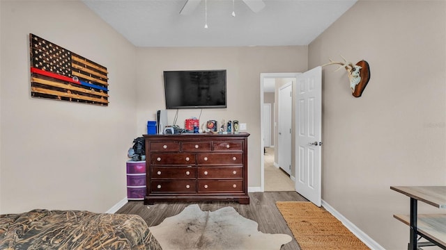bedroom featuring ceiling fan, baseboards, and wood finished floors