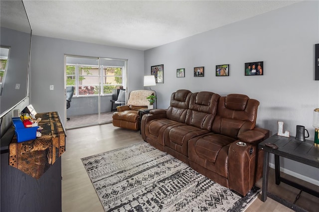 living room with a textured ceiling, baseboards, and wood finished floors