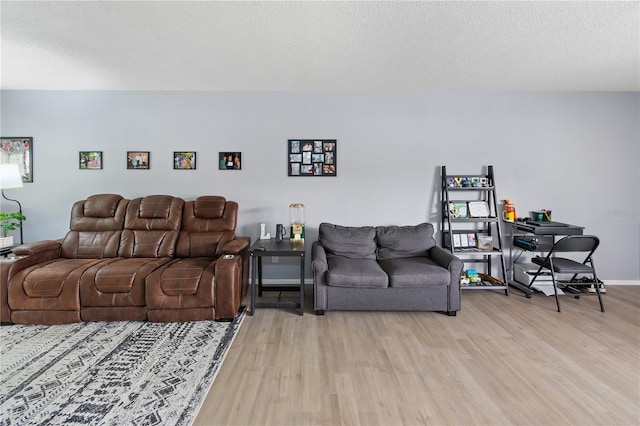 living room with light wood-type flooring, a textured ceiling, and baseboards