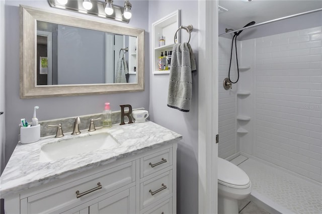 bathroom featuring tiled shower, vanity, and toilet