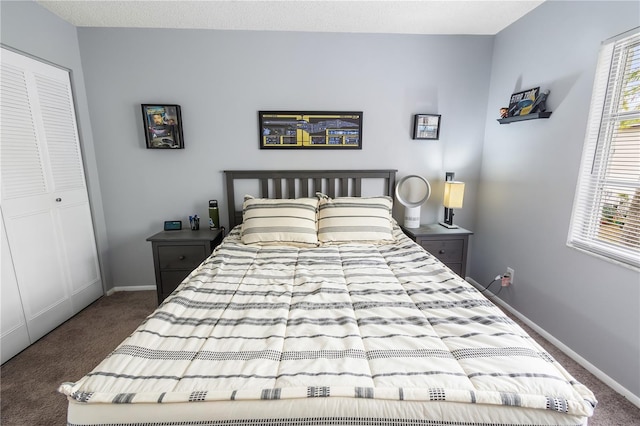 bedroom with a closet, dark carpet, and baseboards