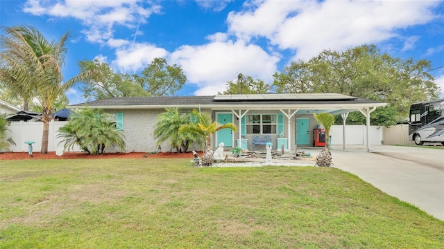 view of front of home featuring solar panels, fence, concrete driveway, stucco siding, and a front yard