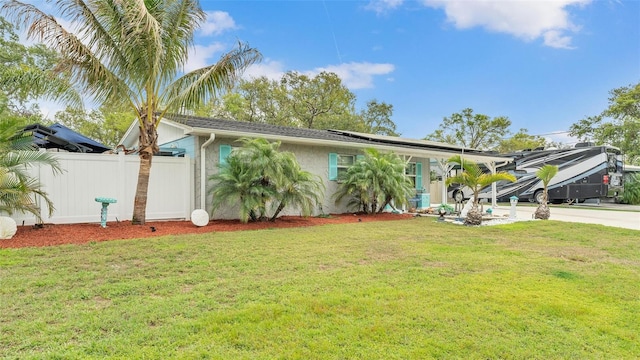 view of front of property with concrete driveway, fence, roof mounted solar panels, a front lawn, and stucco siding