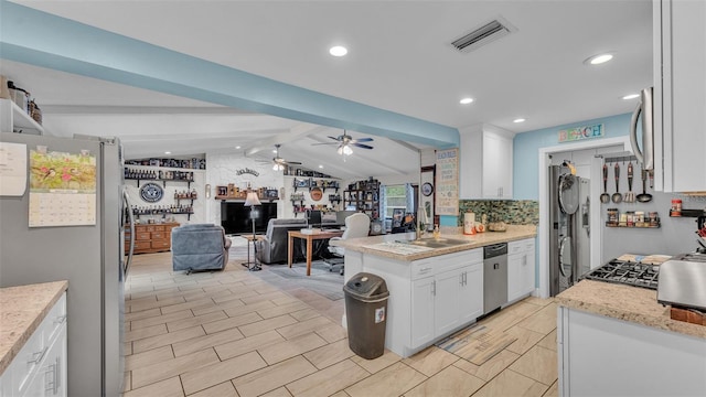 kitchen featuring visible vents, appliances with stainless steel finishes, vaulted ceiling with beams, white cabinetry, and a sink