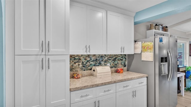 kitchen featuring light stone counters, white cabinetry, backsplash, and stainless steel fridge with ice dispenser