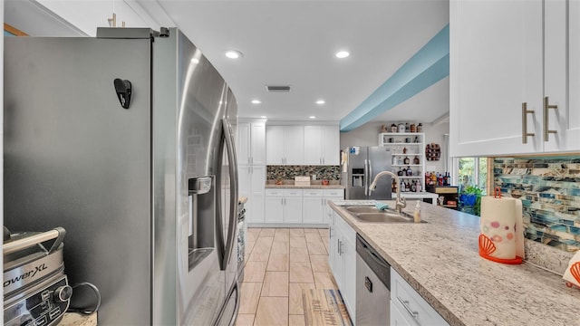 kitchen with visible vents, backsplash, appliances with stainless steel finishes, white cabinetry, and a sink